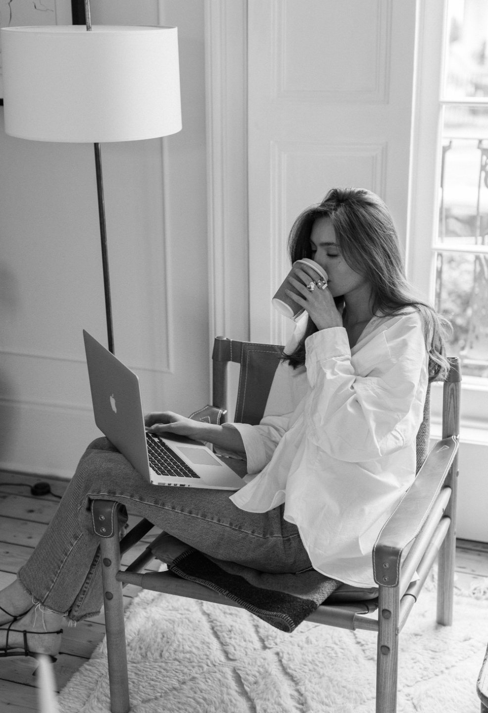 Woman pausing with a cup of tea while working on her laptop