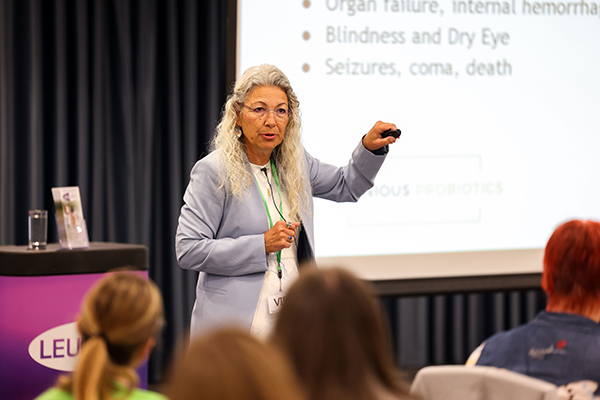 Dr. Judy Morgan gesturing toward a presentation screen while speaking to an audience at a seminar.
