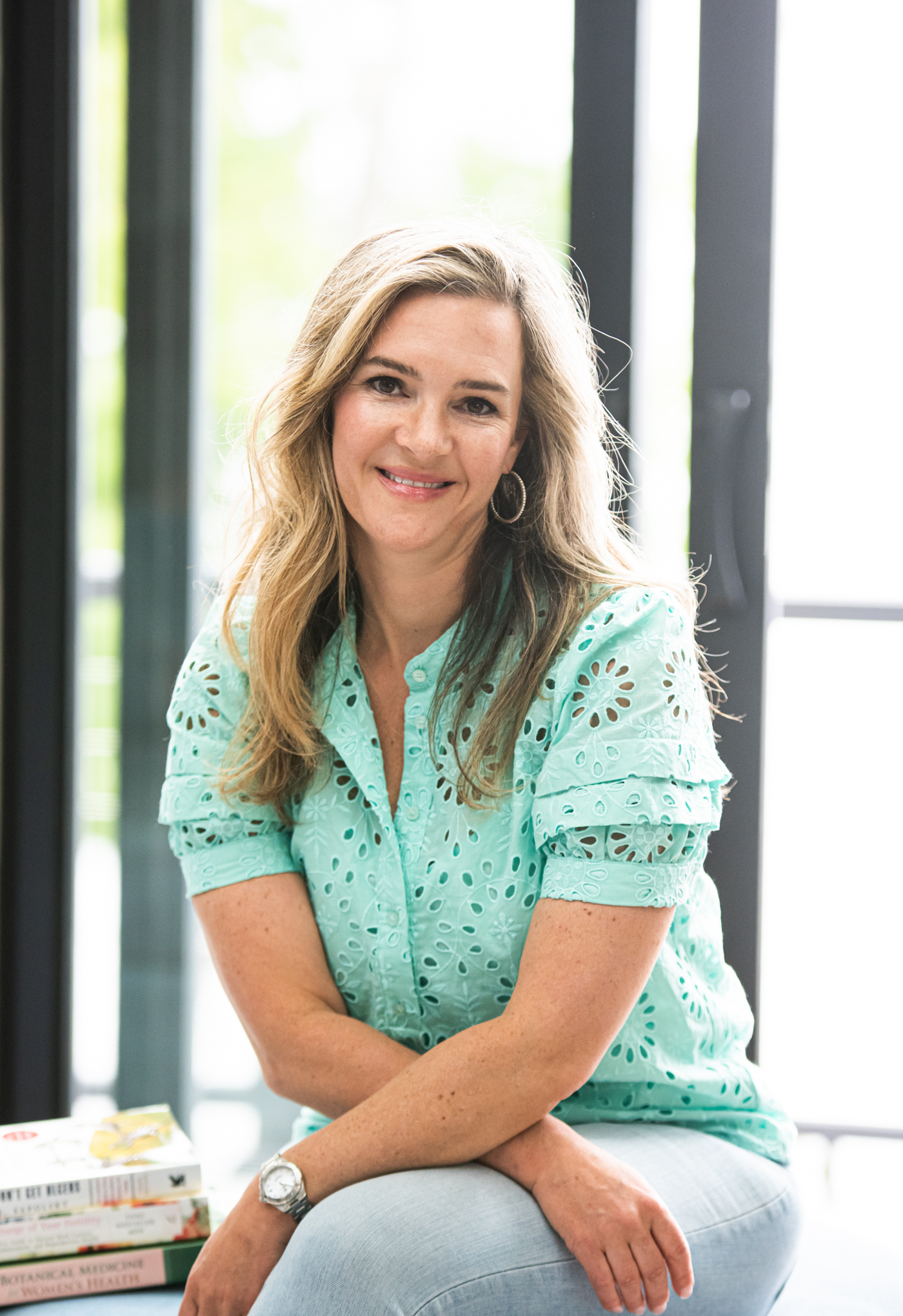 Dr. Jaclyn Smeaton smiling, seated beside a stack of women's health books