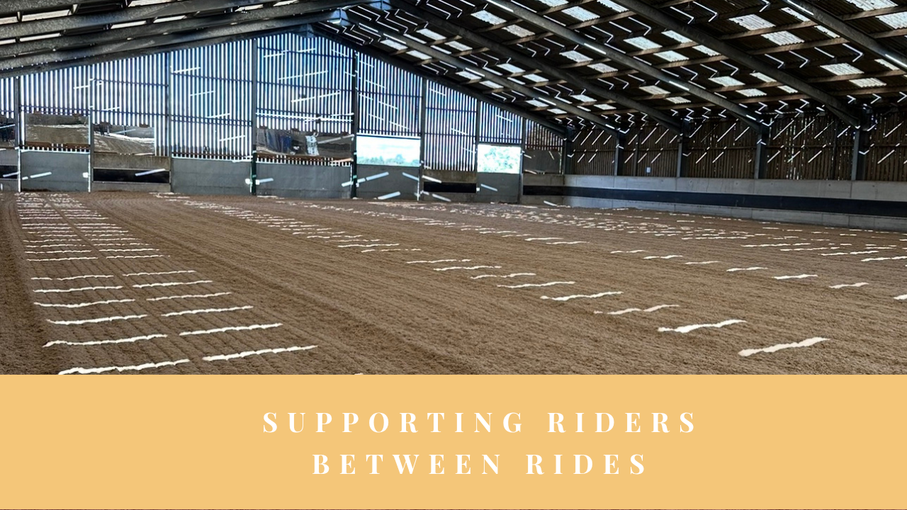 Empty indoor riding arena with the words ‘Supporting Riders Between Rides’.