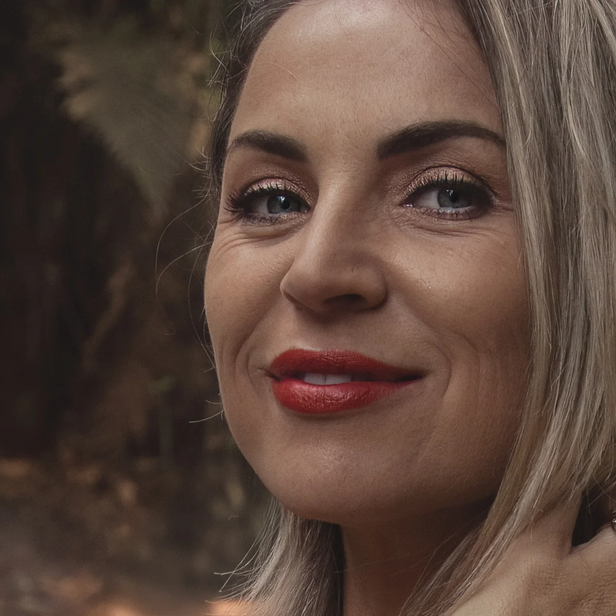 Victoria Bond, close portrait with a soft smile, forest light behind her