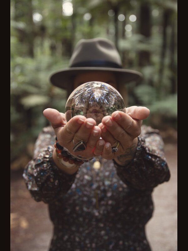 Two hands holding out a crystal ball in a forest.