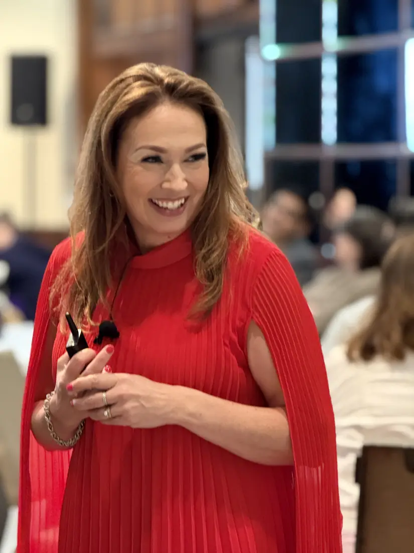 Jennifer Krueger speaking on stage in a red dress
