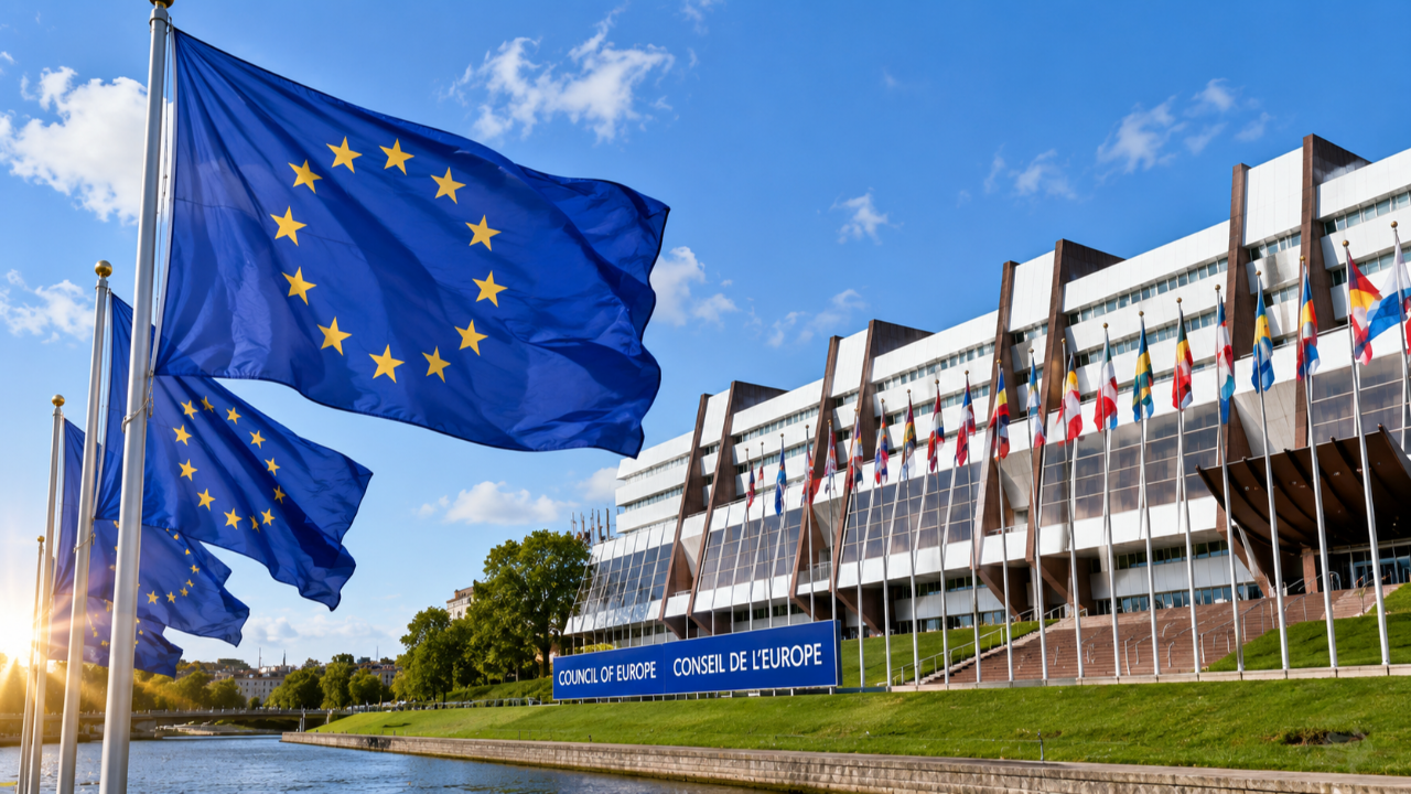 Bandiere europee davanti a un edificio istituzionale, simbolo della Convenzione di Lisbona, della cooperazione internazionale e del riconoscimento delle qualifiche nell'istruzione superiore europea.