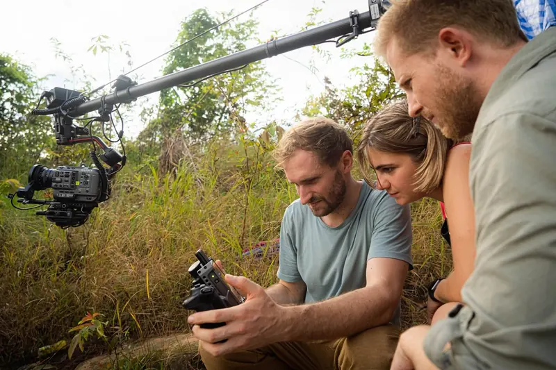 Three filmmakers checking a camera on a gimbal and boom
