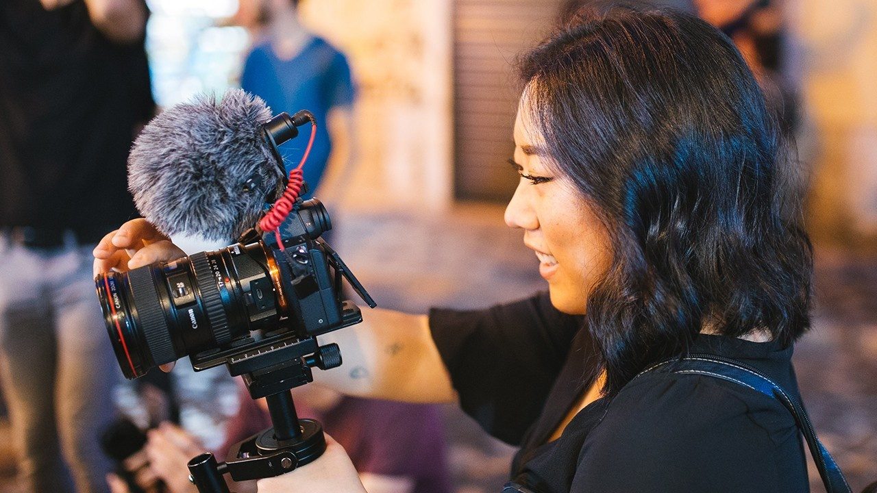 Solo filmmaker recording audio with a shotgun microphone on set