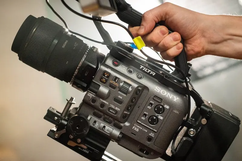 A close-up of a hand holding a cinema camera