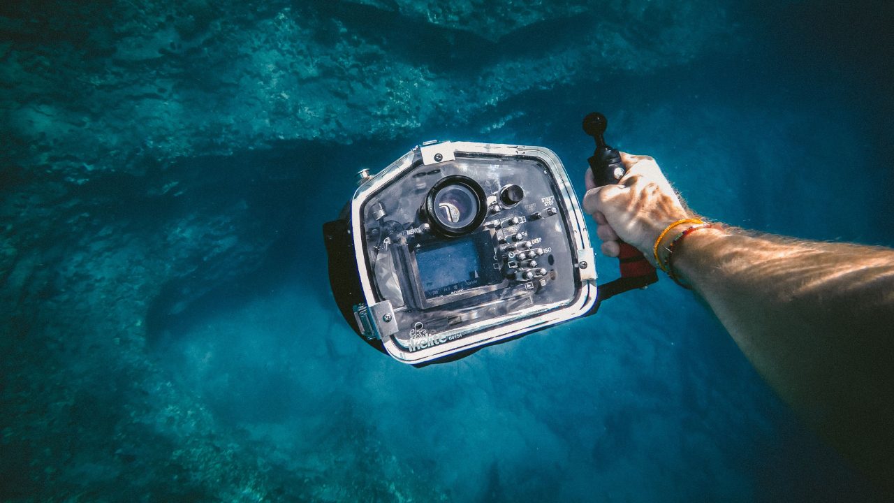 Underwater camera housing held by diver filming a documentary on location