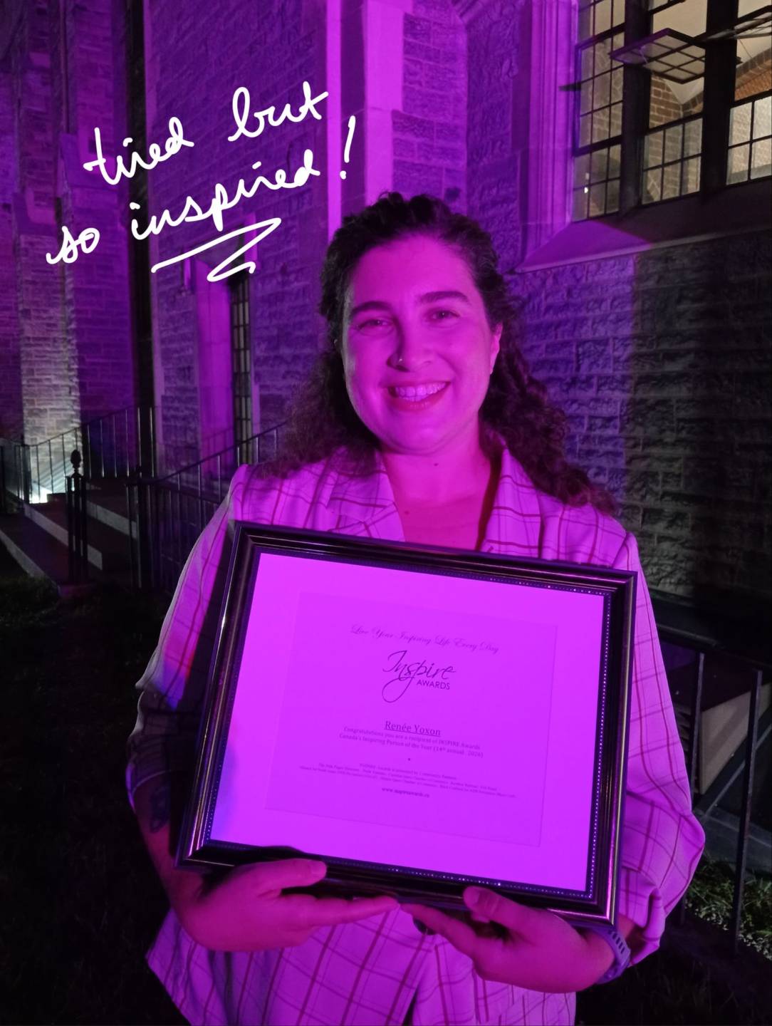 Ren&eacute;e smiling with their award, bathed in pink light, under the text 