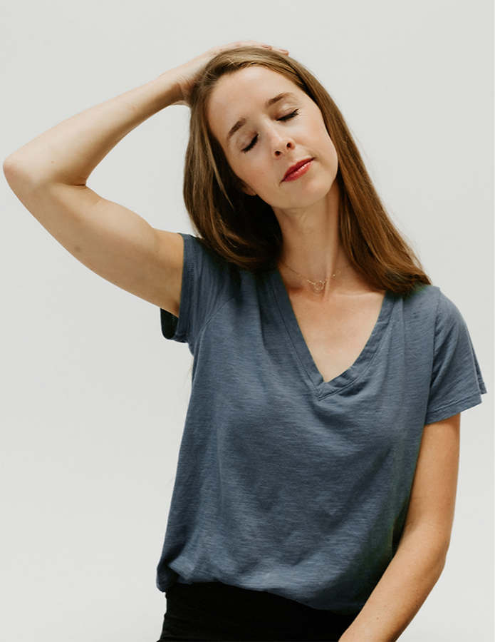 A woman demonstrating a gentle neck stretch as part of a body-based calming practice.