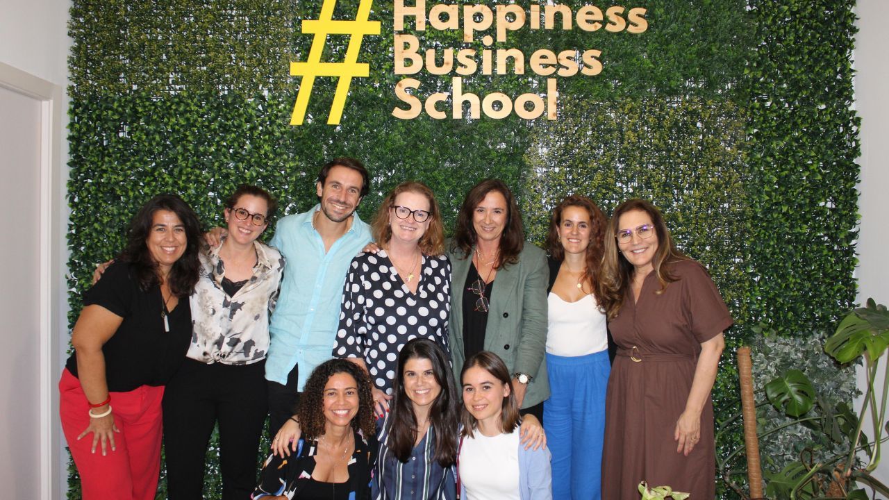 Uma Equipa do MBA da Happiness Business School junto ao logótipo da escola