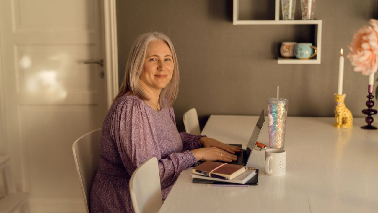 Margrethe sitter ved bordet og smiler.