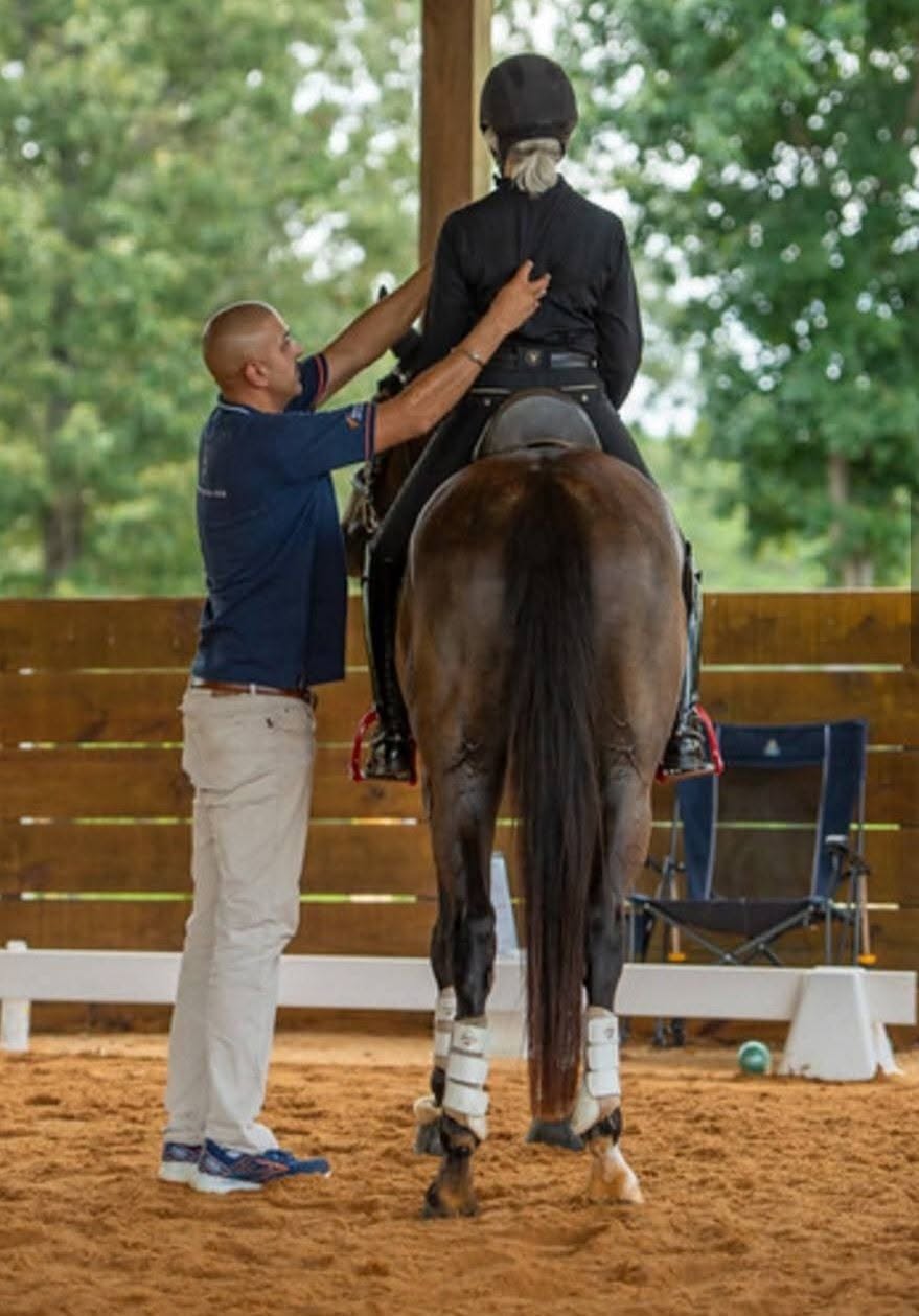 Dave Thind offering hands-on guidance to a mounted rider during a clinic