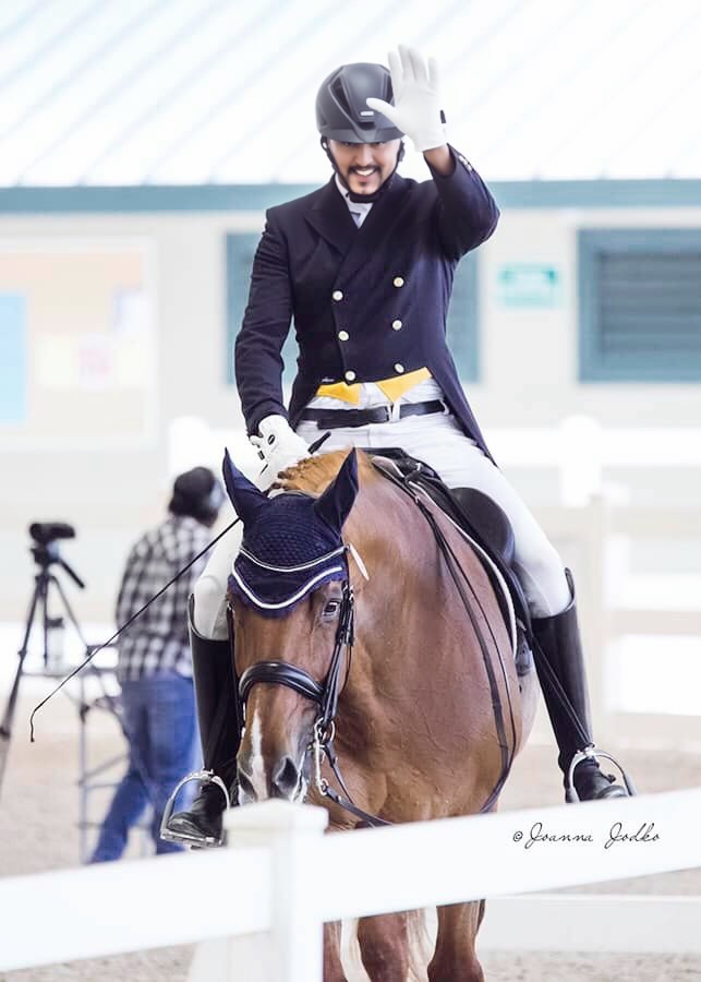 Dave Thind smiling and waving to the audience from horseback after dressage riding