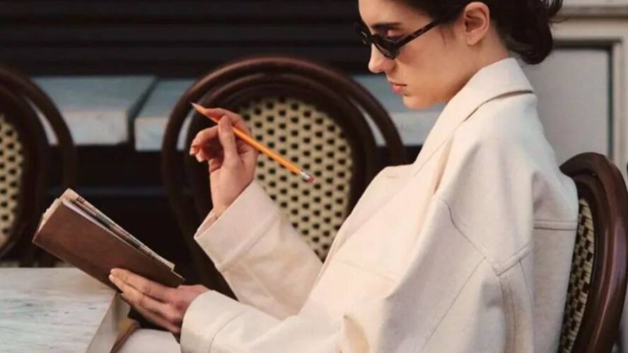 Woman revising a printed self-review at an outdoor table.