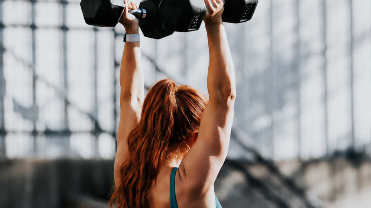 A woman over 40 lifting two barbels