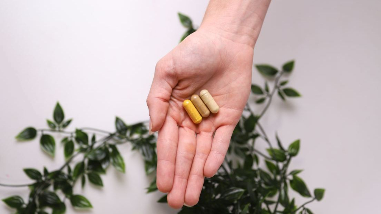 Hand holding multivitamin capsules for women’s energy, hormone balance, and immune support.
