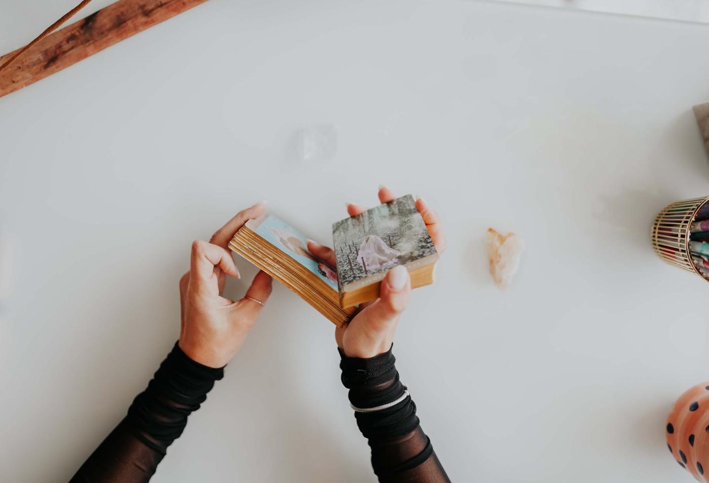 Shelly's hands shuffling a gold-edged tarot deck