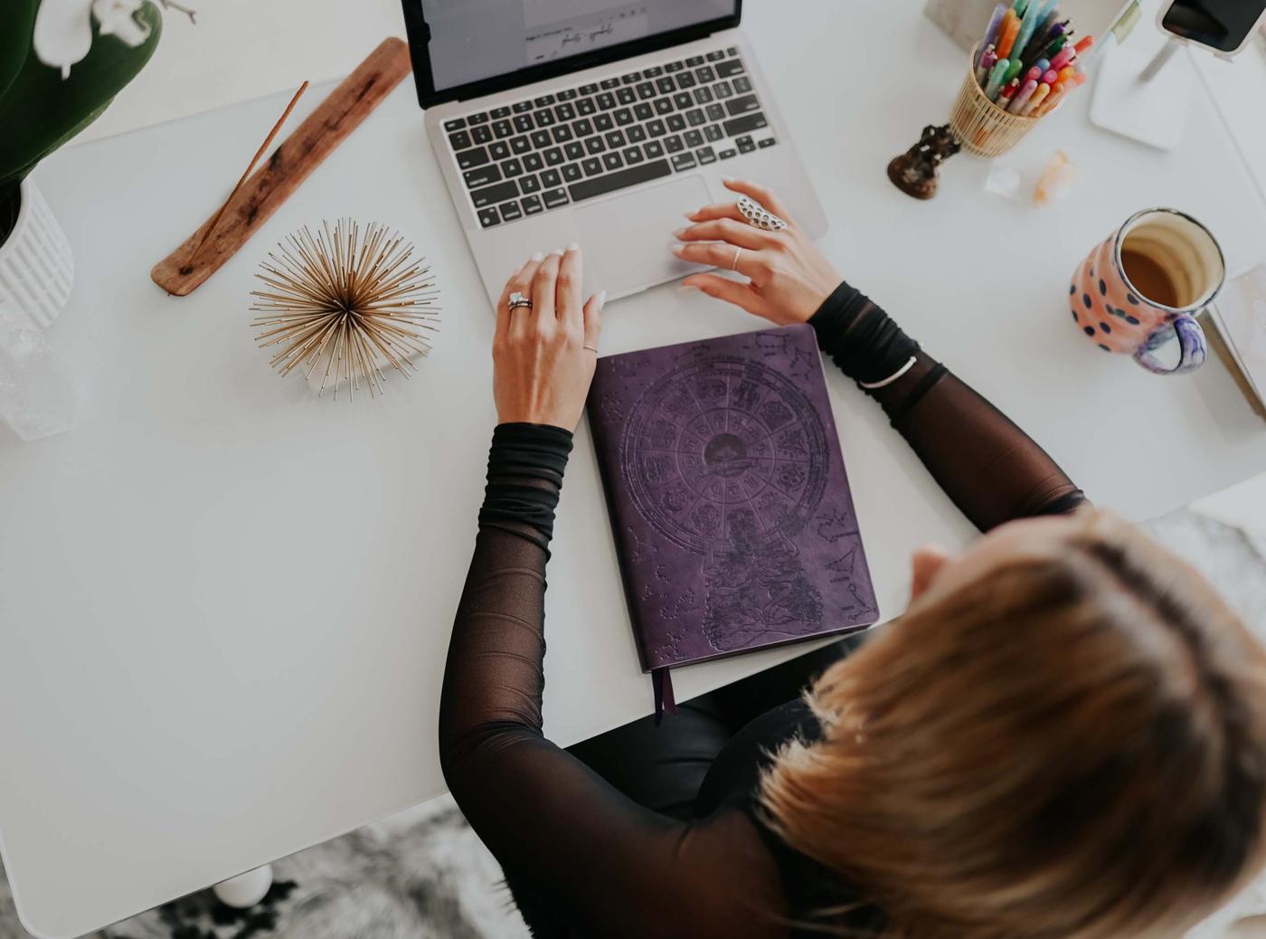 Shelly at her desk with her laptop and an astrology journal