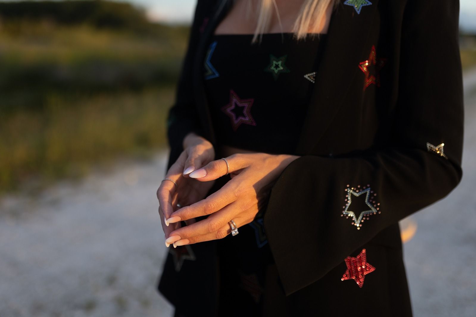 Shelly's hands at golden hour against a black jacket scattered with sequin stars