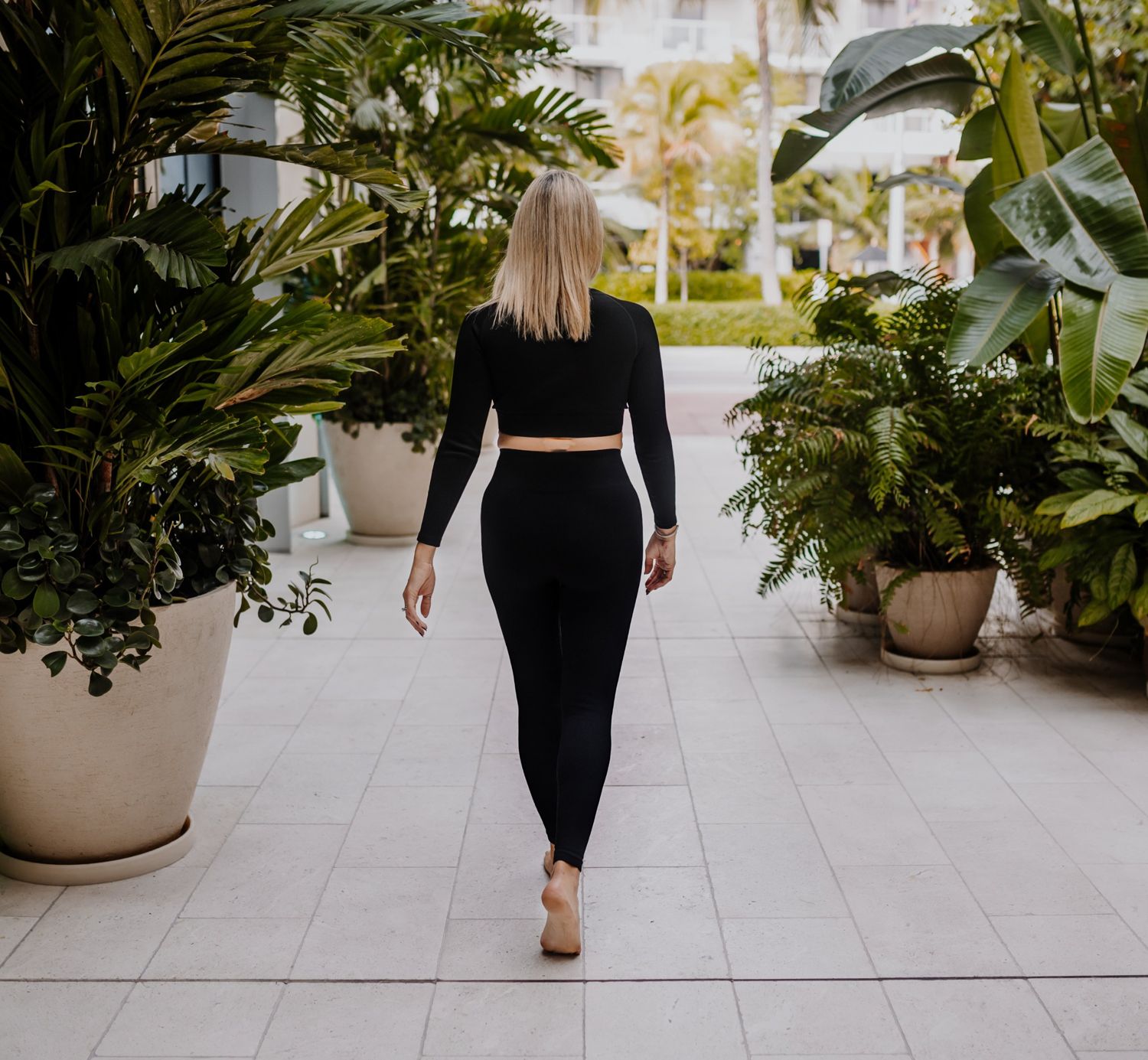 Shelly walking barefoot down a palm-lined path, away from the camera