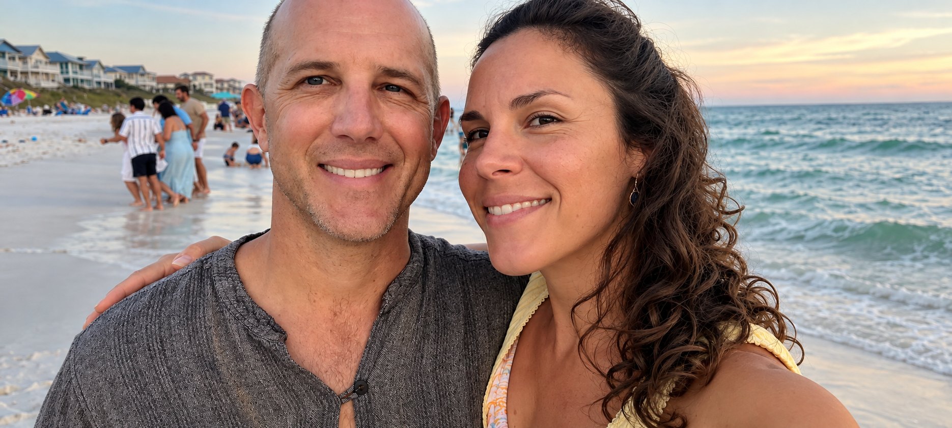 Courtney and her husband Eric smiling together on the beach at sunset