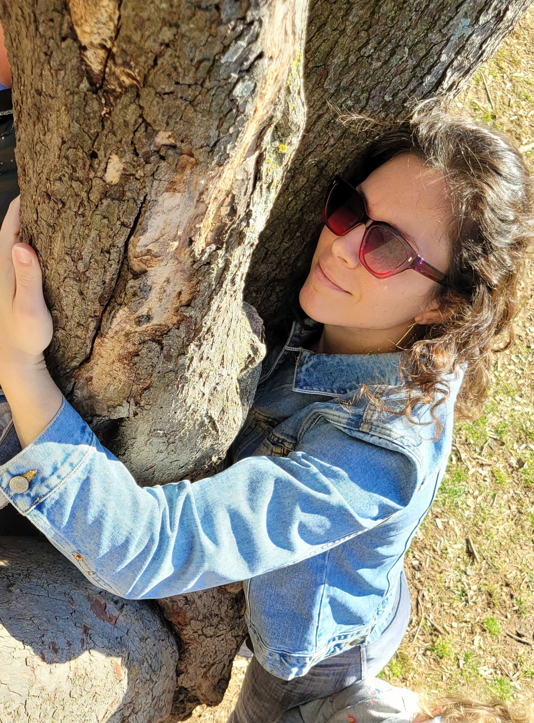 Courtney hugging a tree in the sunshine