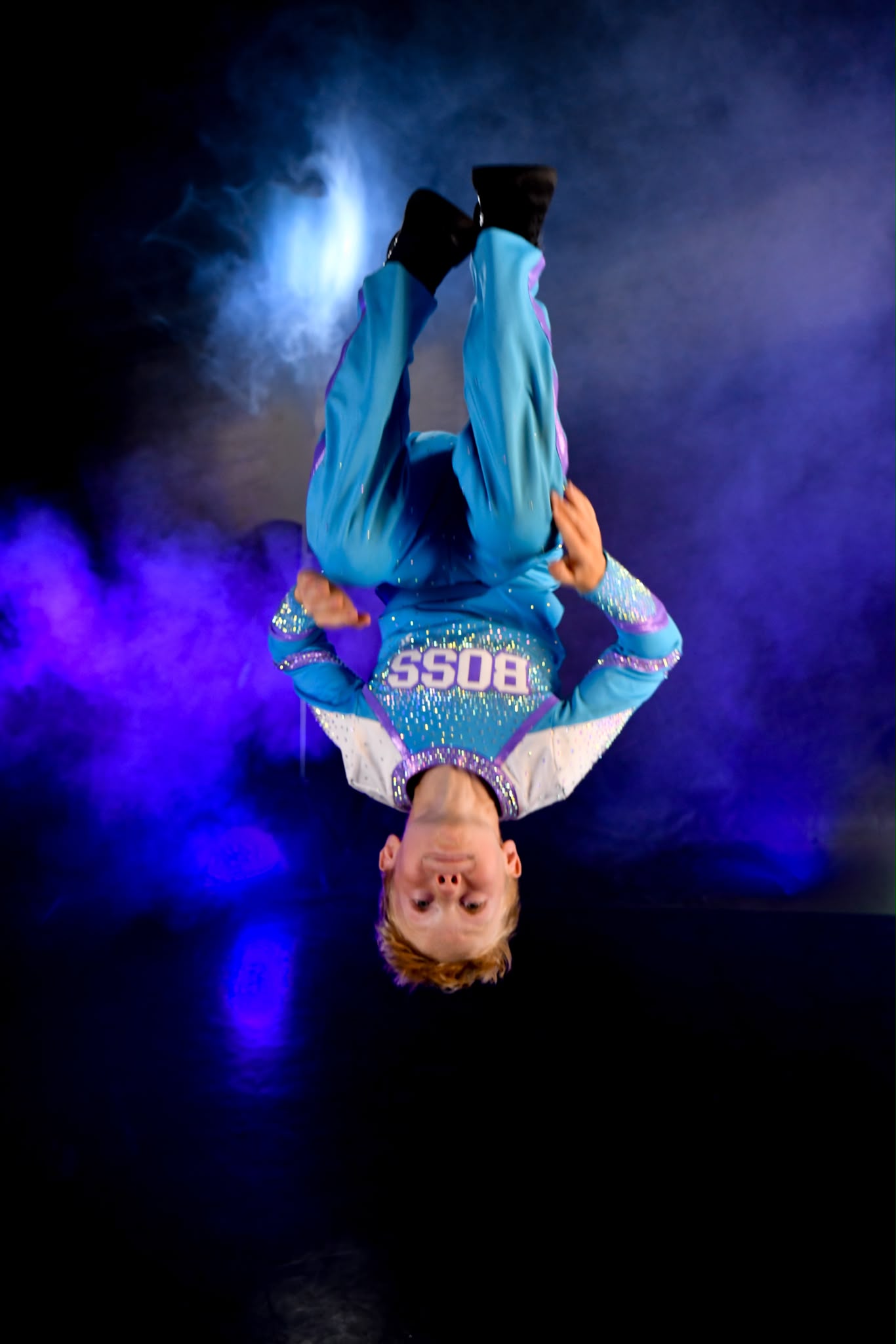 Dynamic Athlete Portrait: athlete mid-flip under stage lighting and haze