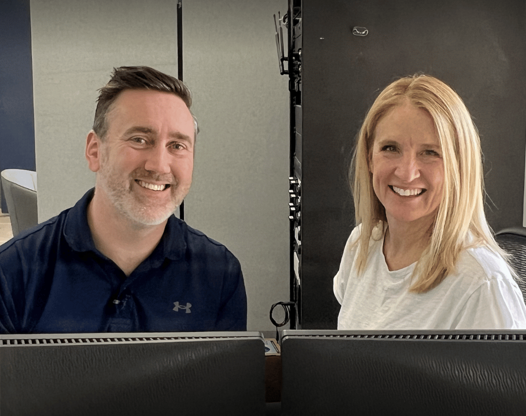Kathy Mauck and Matt Bush, Founders of Next Level Neuro, sitting together behind a computer desk, smiling at the camera