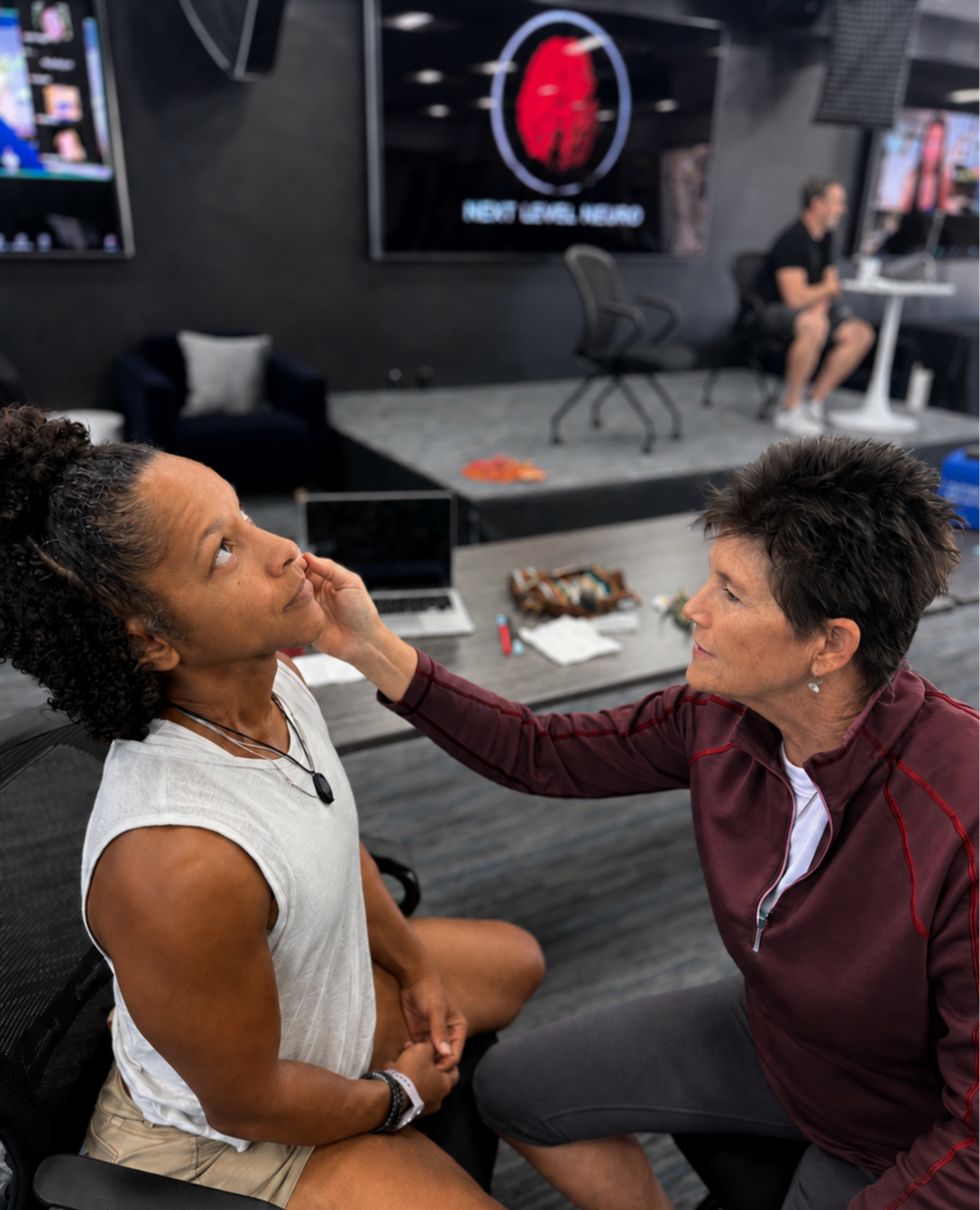 Two female Next Level Neuro students sit together in a classroom setting, working on sensory retraining for the face, at a live workshop