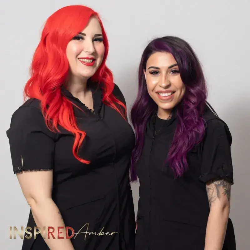 Inspired Amber permanent makeup academy instructor posing alongside a smiling student graduate in matching black studio uniforms.