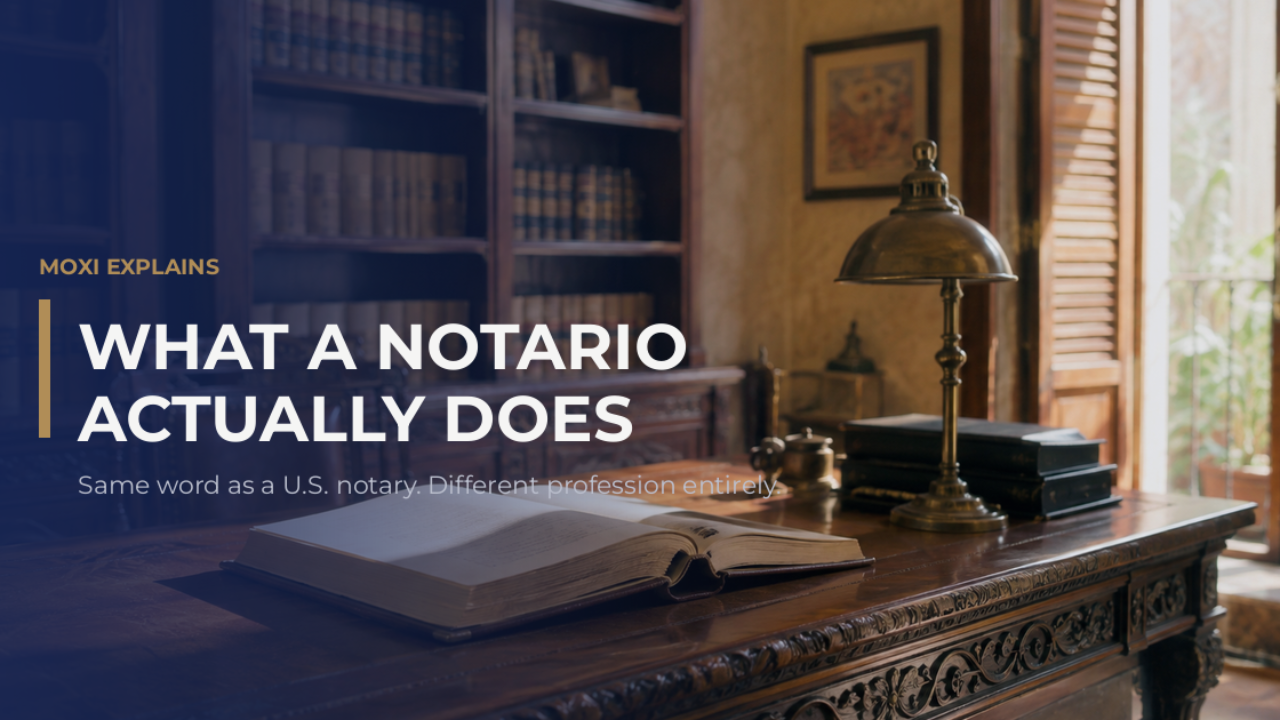 A Mexican notario's office with a bound protocol volume open on a carved wooden desk, shelves of legal registers behind.