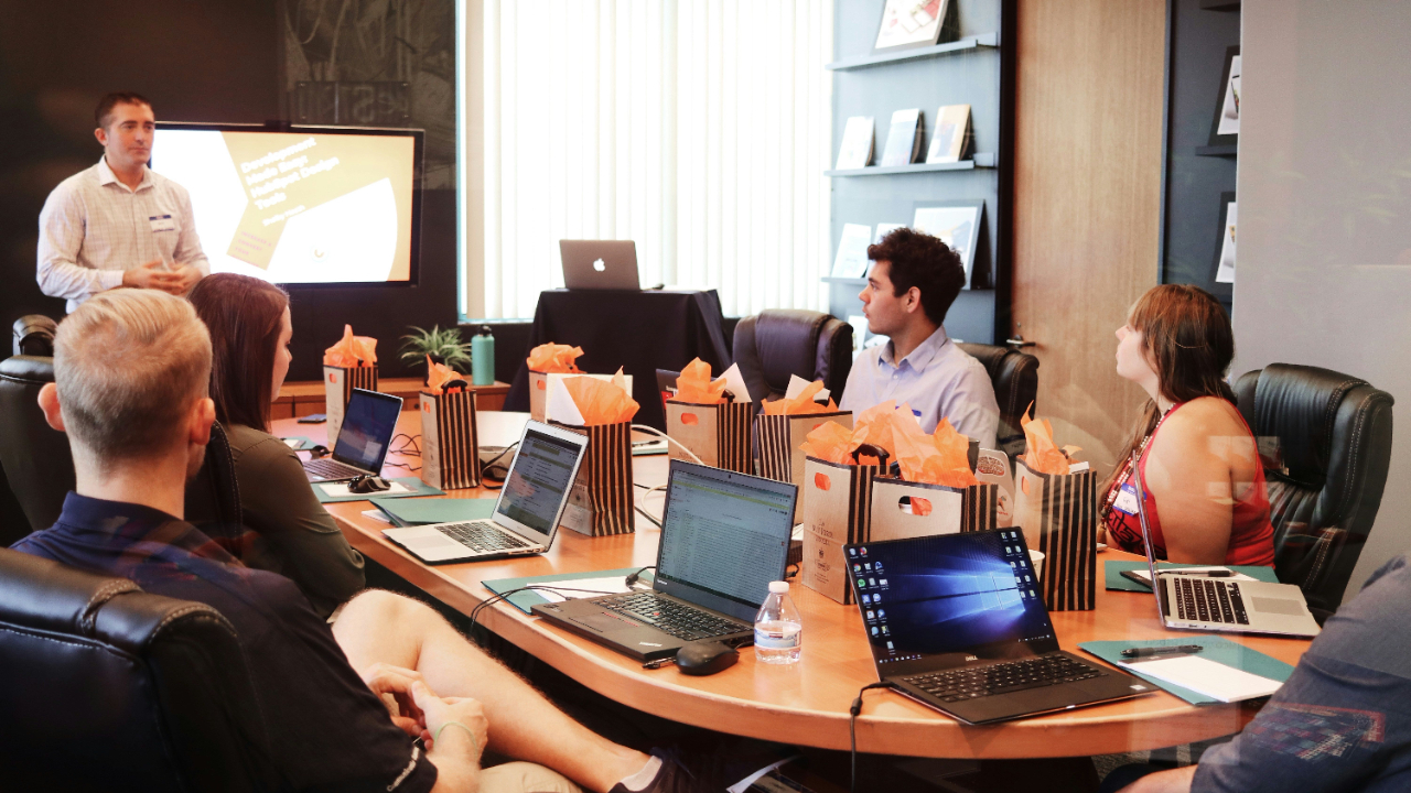 Nervous presenter in a meeting presenting to a room of work colleagues with laptops