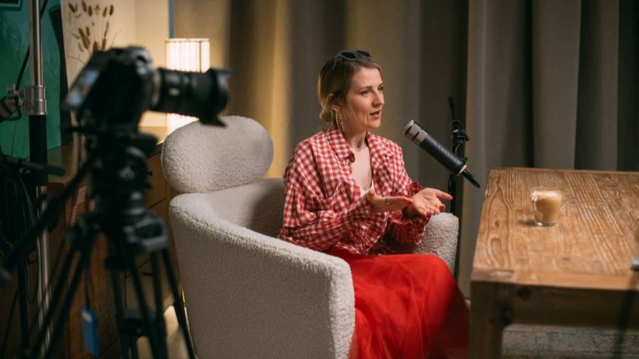 Lady sitting in front of a microphone speaking for a podcast