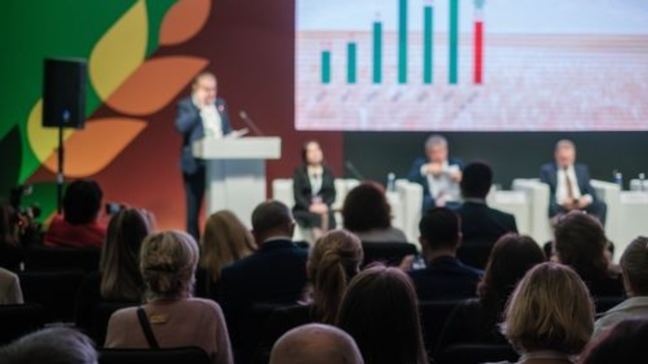 Man public speaking at a conference in front of large audience