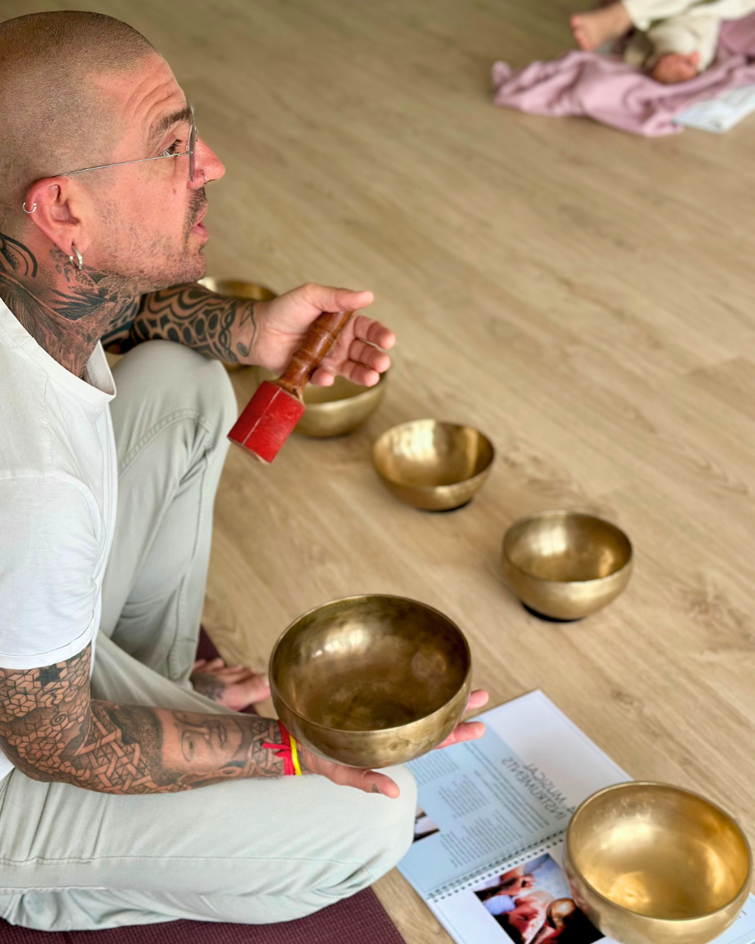 Zeupa sitzt lächelnd im Schneidersitz und hält seine Akustikgitarre in der LaVi Sound und Yoga Academy