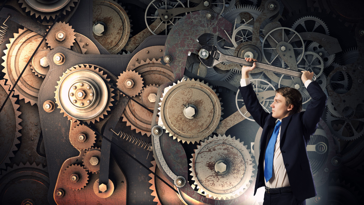 business man with giant wrench turns a gear on a wall made of gears