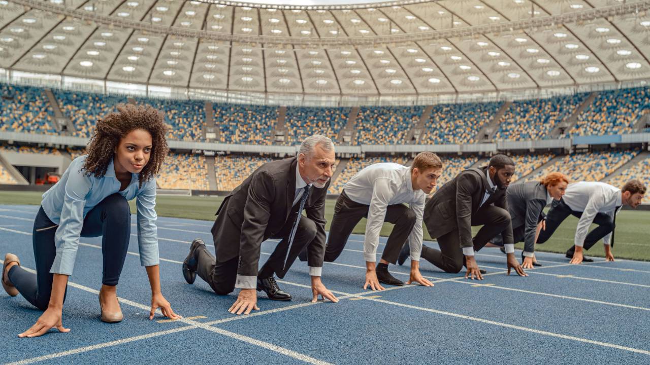 Business people lined up at the start line of a sprint in a stadium setting