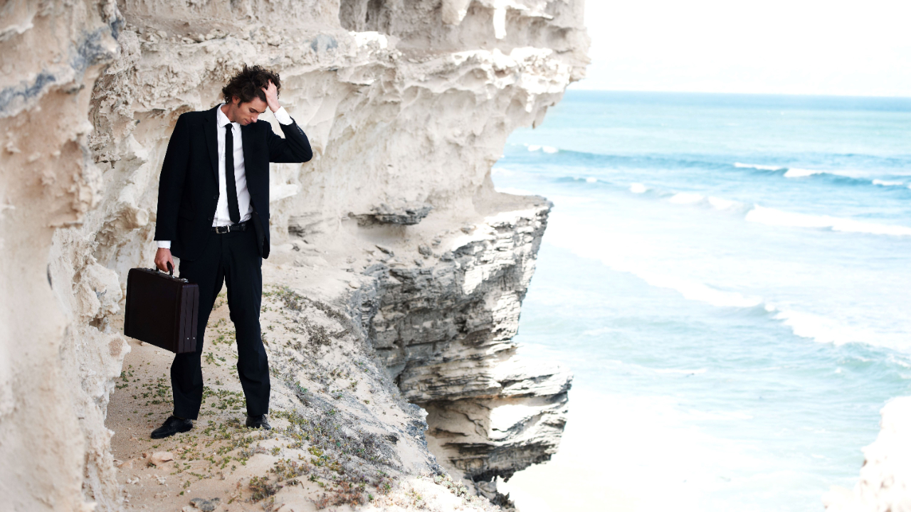 Worried businessman walking along the edge of a cliff
