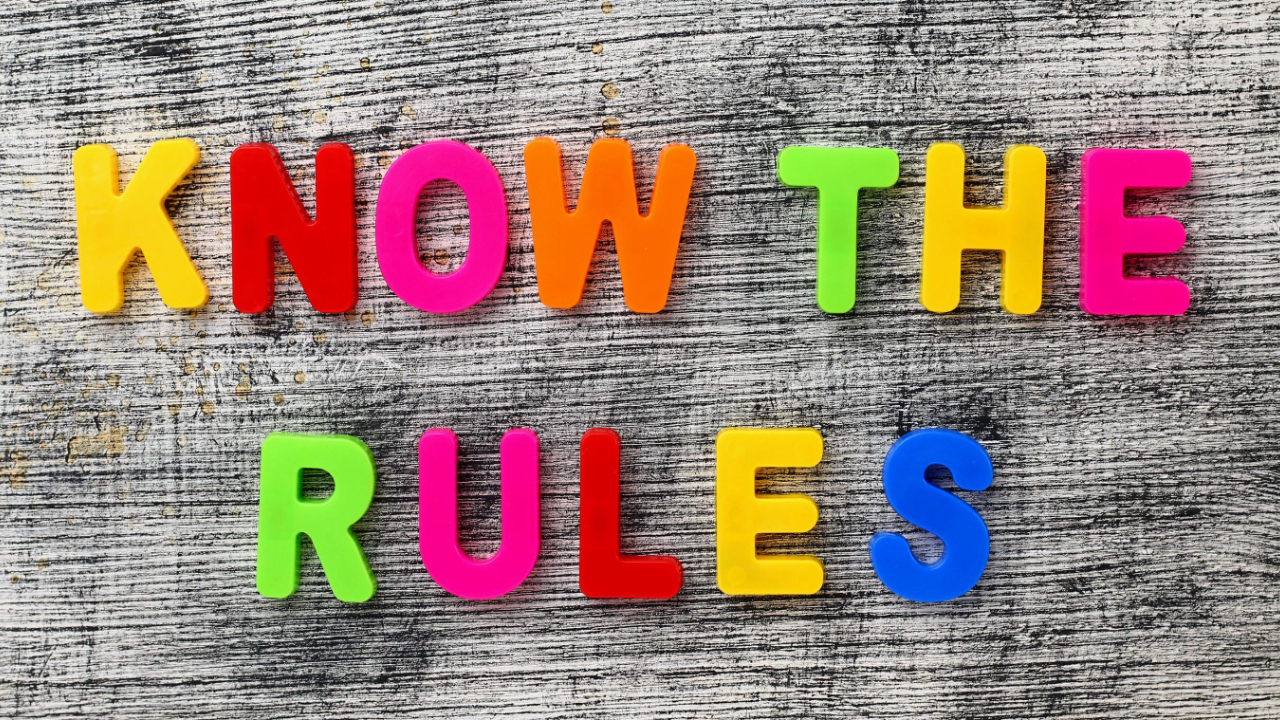 Wood board with the words KNOW THE RULES in multicolored letters