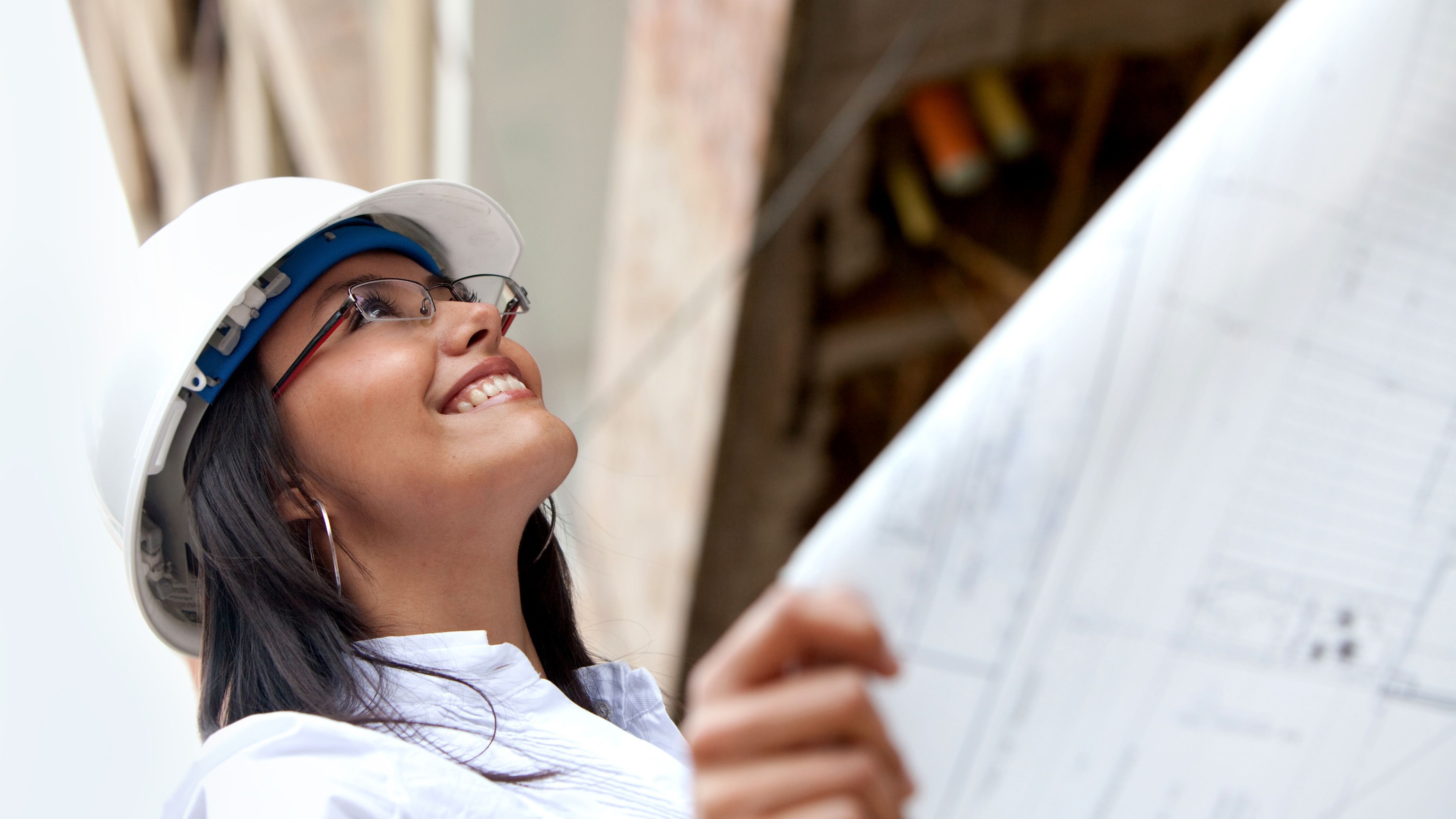 Female engineer looking up while holding construction blueprints