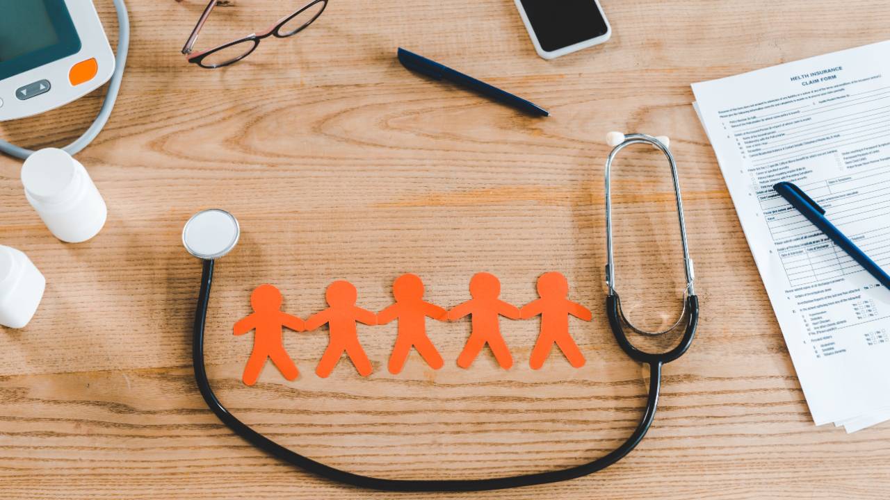 Stethoscope with orange human shapes plus smartphone and blank medical paperwork