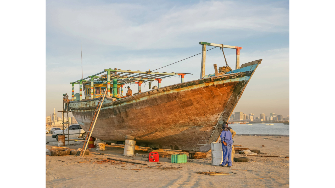 two men inspecting an old boat on the beach