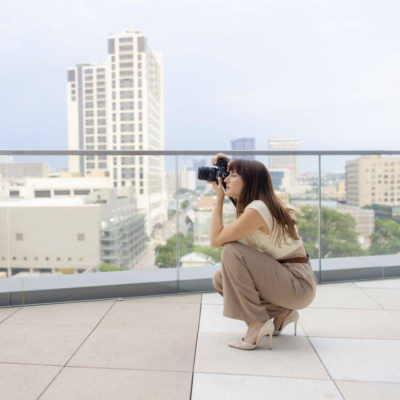 Vanessa Joy crouching to photograph a cityscape from a rooftop terrace