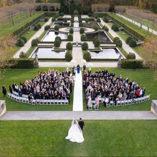 Aerial view of an outdoor wedding ceremony in a manicured garden