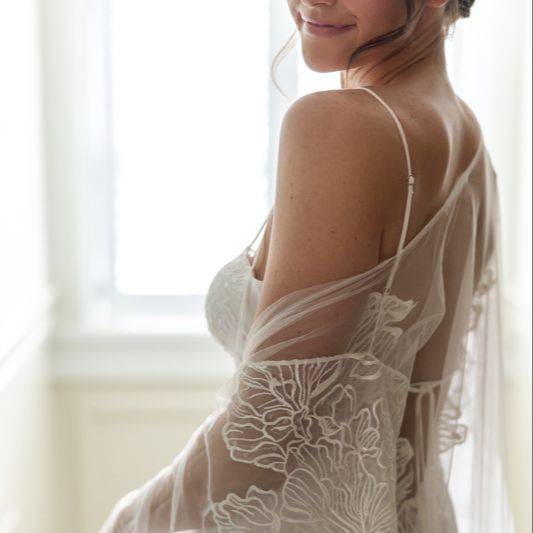 Bride in a sheer lace gown, close-up of her back, lit by window light