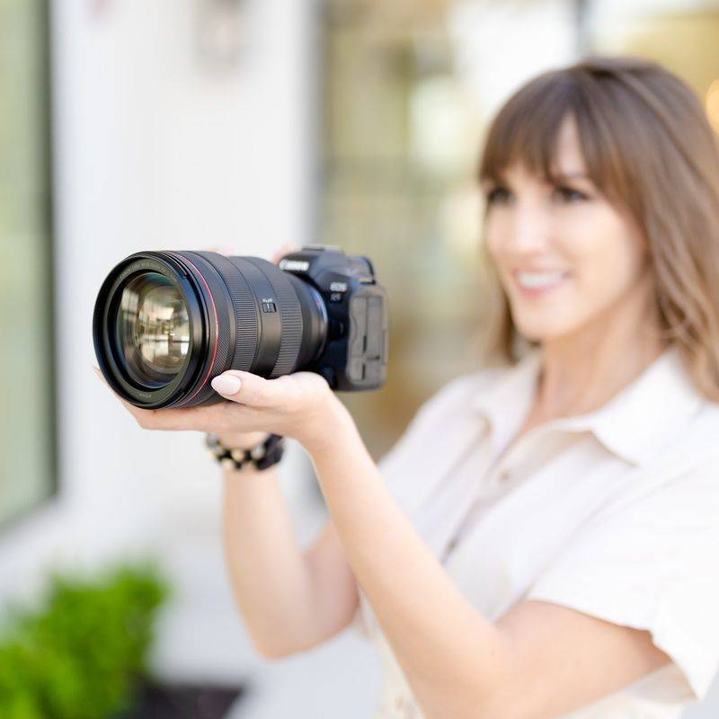 Vanessa Joy holding a Canon mirrorless camera, part of her wedding photography equipment list