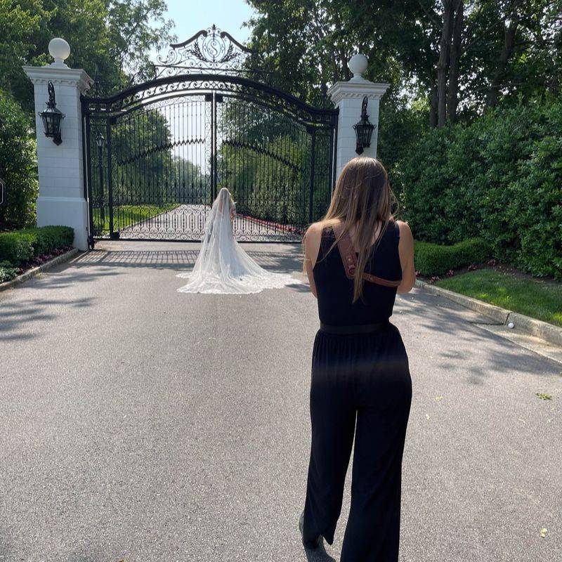 Vanessa Joy photographing a bride in a flowing veil walking through an iron gate