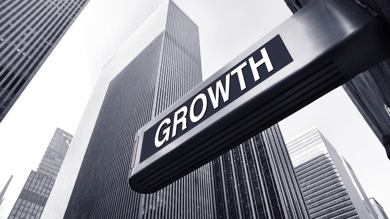 A black and white street sign reading Growth photographed from below against towering city skyscrapers, representing the Inner Empire™ principle that real reinvention in midlife is not about doing more but about unveiling the woman who was always already there.