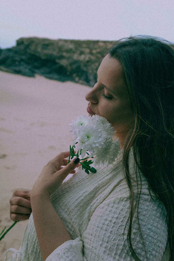 Inês a cheirar uma flor junto ao mar